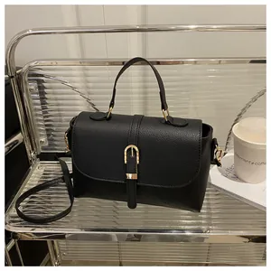 Detailed close-up of a black lychee texture leather handbag with elegant gold metal buckles