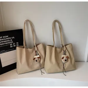Détail d'un sac cabas en toile kaki avec broderie et pendentif chien en peluche