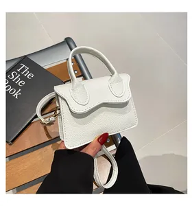Détail de la texture cuir de litchi blanc et des finitions dorées sur le mini sac à main
