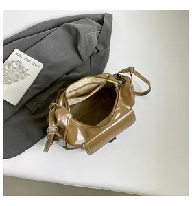 Detail of dark brown glossy handbag interior with zipper pocket on gray blazer