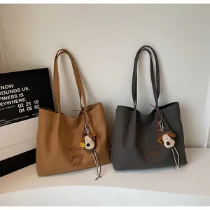 Détail de sacs fourre-tout en toile avec broderie de lettres et breloques de chiot