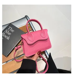 Détail du mini sac à main rose en cuir grainé avec rabat et poignée ronde élégante