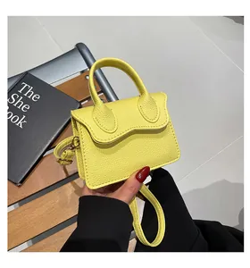Détail d'un sac à main jaune en cuir grainé avec rabat ondulé et bandoulière réglable