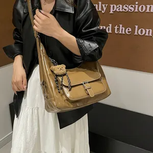 Khaki brown leather tote bag with buckle front pocket and bear charm on a model