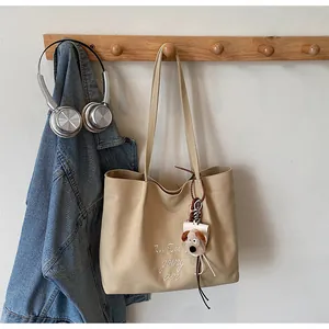 Détail du sac cabas en toile beige avec broderie et porte-clés chiot en peluche
