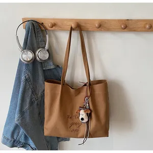 Détail du sac fourre-tout en toile marron avec broderie 'But Life going on' et charm peluche