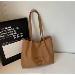 Gros plan du sac cabas en toile caramel avec broderie détaillée et anses solides