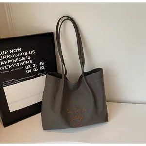 Détail de la broderie orange sur le sac cabas en toile grise avec fines lanières