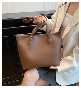 Detail of brown PU leather tote bag featuring golden buckle and brand logo lettering