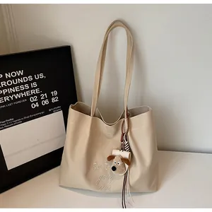 Détail de la broderie et du charm de chien en peluche sur le sac fourre-tout en toile beige