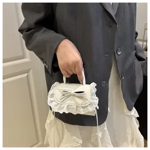 Mini white bow shoulder bag featuring delicate lace pleated edges held by a model