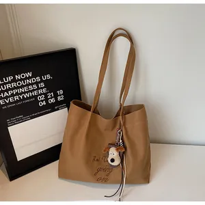 Détail du sac cabas en toile marron avec broderie artistique et breloque chien peluche
