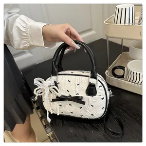 Detail of white pleated handbag with black bow prints and delicate pearl lace pendant