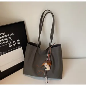 Détail du sac cabas en toile gris foncé avec broderie et porte-clés chien en peluche