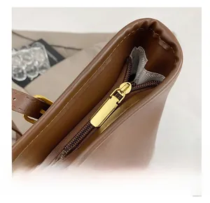 Macro shot of smooth gold zipper and dark brown leather texture on a tote bag