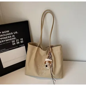 Détail d'un sac cabas en toile avec broderie blanche et charmant porte-clés chiot