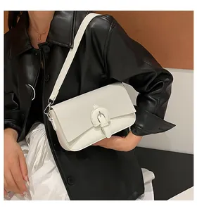 Gros plan du sac bandoulière blanc tressé avec boucle argentée sur veste en cuir noir