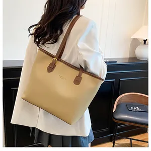 Close-up of contrast large tote bag with dark brown straps and brand logo detail