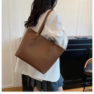 Detailed back view of a large brown tote bag on a model in white blazer for size reference
