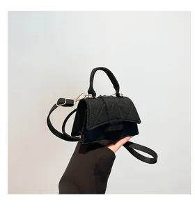 Detail of black quilted felt crossbody bag with gold hardware and removable strap