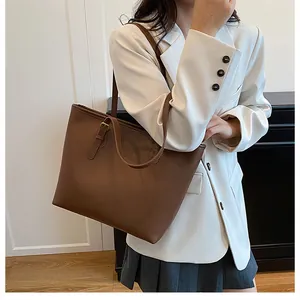 Close-up of a large brown leather tote bag showing smooth texture and long shoulder straps