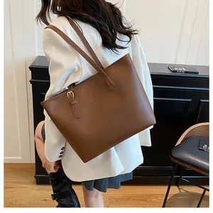 Detail view of brown leather tote bag with gold buckle and adjustable shoulder strap