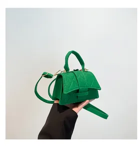 Close-up of green quilted texture and stitching on a small fashion square handbag