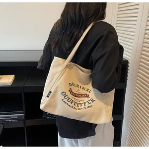 Detalle del bolso tote de lona crema con letras retro y correa de hombro resistente