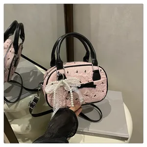 Detail of pink bowling bag with black bow embroidery and pearl lace charm accessory