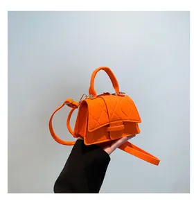 Macro detail of bright orange quilted felt handbag showing unique curved base and texture