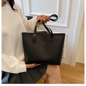 Detail view of black leather tote bag with gold lettering and adjustable shoulder strap