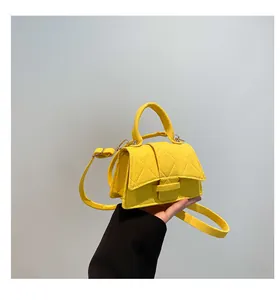Detail of yellow quilted leather crossbody bag featuring top handle and metallic hardware
