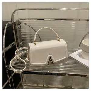 Detail of white mini crossbody bag featuring a golden V-shaped metal buckle and smooth leather