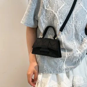 Mini black quilted trapezoid handbag with gold hardware shown on a model