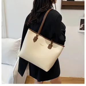 Close-up of contrast stitch tote bag with gold KMDER logo and brown leather handles