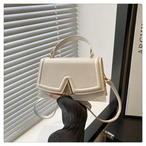 Detailed macro view of the cream leather square bag featuring a gold V-shaped metal buckle