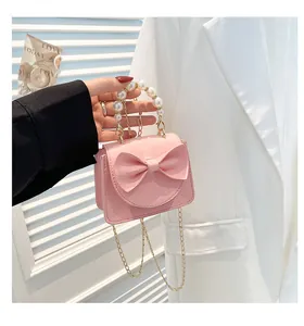 Close-up of pink mini bag with elegant pearl handle and stylish bow detail texture