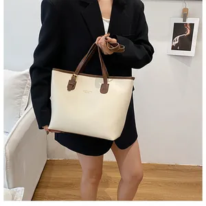 Detailed shot of white PU leather tote bag with brown trim and gold logo on model
