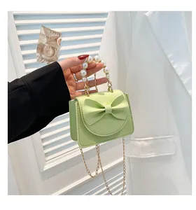 Detail of mint green mini bag showing faux leather texture, bow, and pearl handle