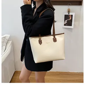 Detail of cream tote bag with brown straps styled with a professional black blazer