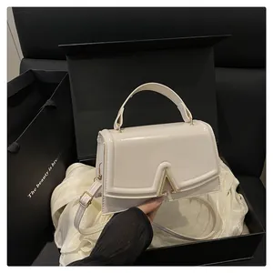Close-up of off-white leather handbag with gold metal clasp and premium gift box