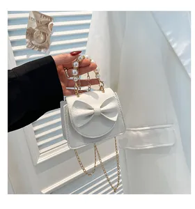 Close-up of white mini square bag featuring lychee texture, bow, and pearl chain handle