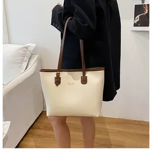 Close-up of beige tote bag with brown leather handles and XMDER & BAGS FASHION logo