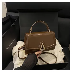 Brown glossy handbag with gold V-buckle presented in an elegant gift box set