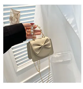 Detailed close-up of beige lychee grain mini bag with bow and pearl handle