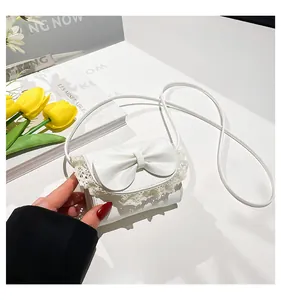 Close-up of white mini crossbody bag featuring a large bow and delicate lace trim detail