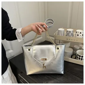 Detailed close-up of silver metallic handbag featuring gold chain straps and a deer charm