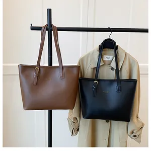 Detail of elegant black and brown leather tote bags with minimalist golden fashion lettering
