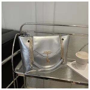 Detail of silver metallic tote bag with golden reindeer charm and elegant hardware lock