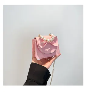 Close-up of pink mini bag with pearl handle, litchi texture, and bow detail